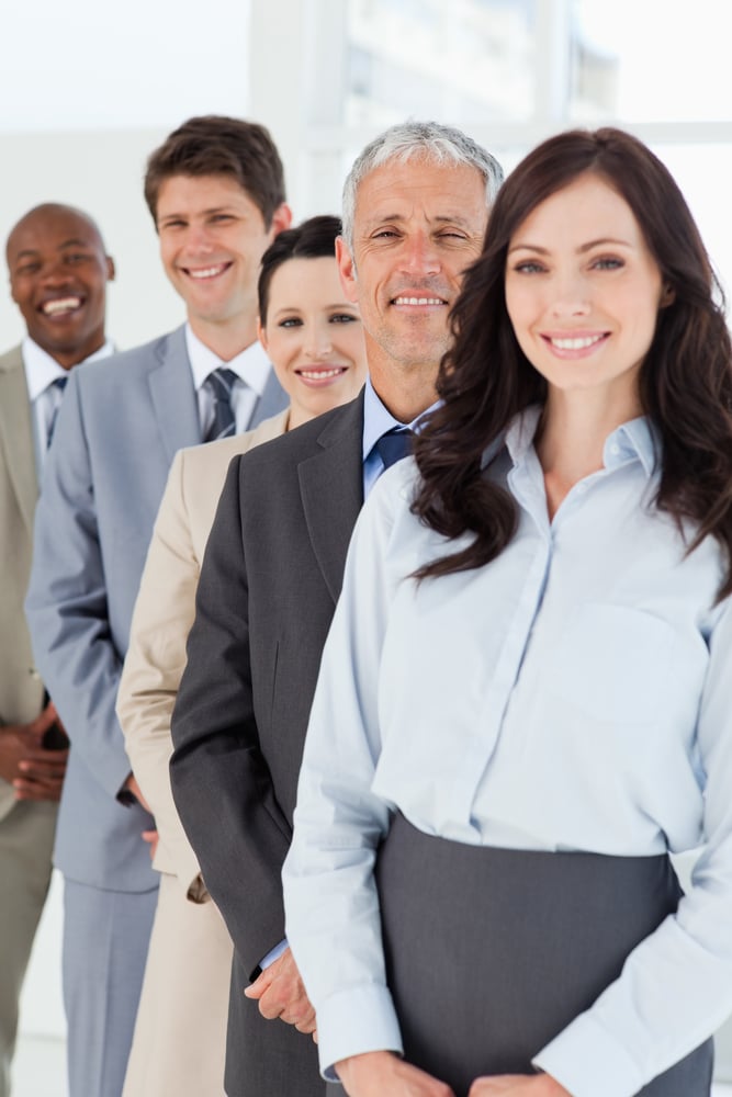 Confident and mature manager standing among his smiling employees